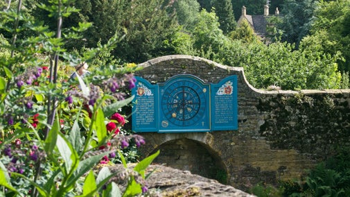A view of the Nychthemeron Clock with some flowers in the foreground at Snowshill Manor, Gloucestershire